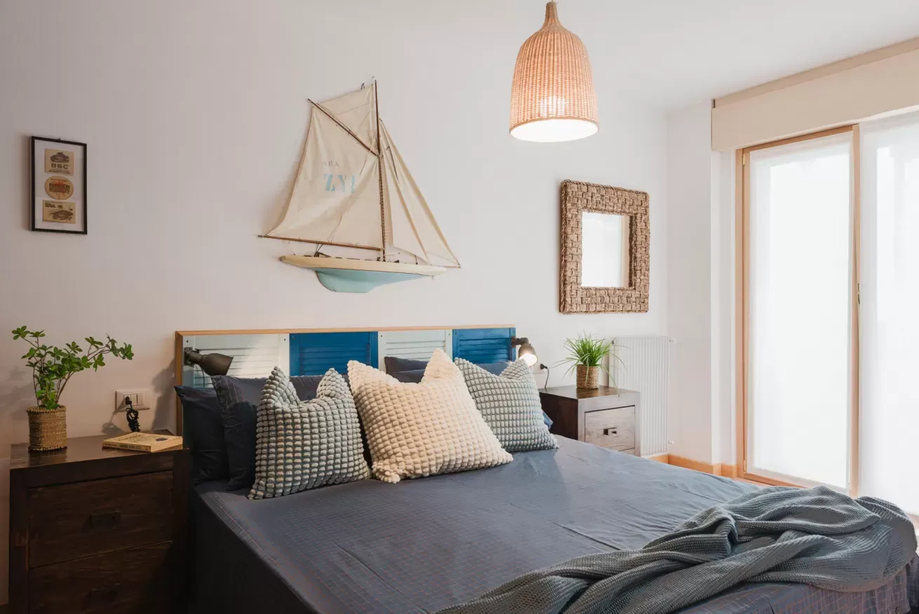 Camera da letto luminosa con letto matrimoniale, cuscini decorativi e arredi in stile marino