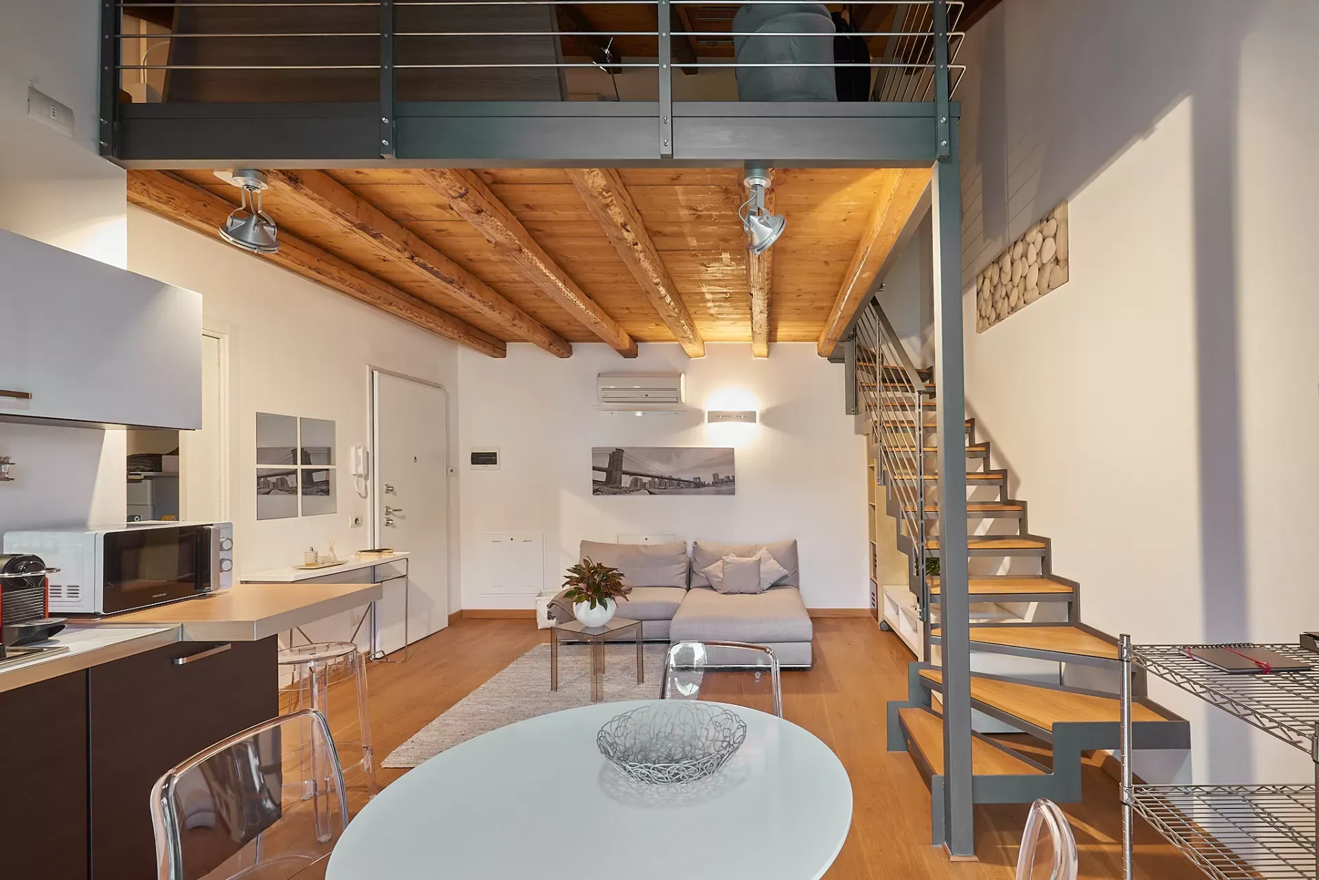 Interno di un loft moderno con soppalco, scala in metallo e soggiorno con cucina a vista