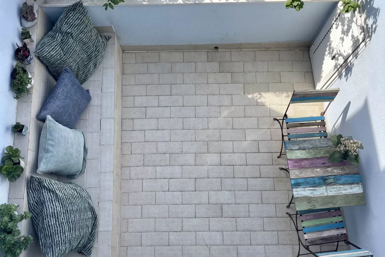 Terrazza con divanetto, cuscini, piante in vaso e tavolo e sedie colorate