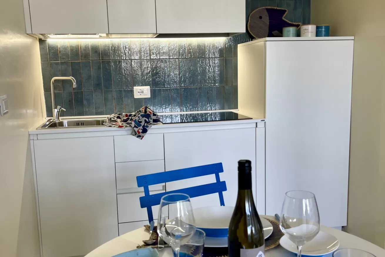 Cucina moderna bianca con tavolo apparecchiato in primo piano