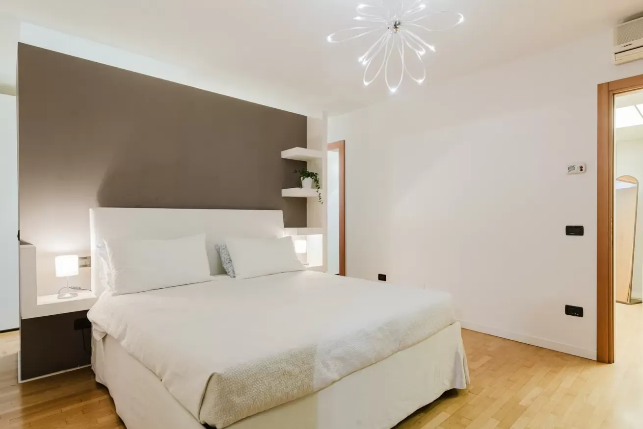 Camera da letto moderna con letto matrimoniale, parete d’accento marrone e lampade da comodino integrate