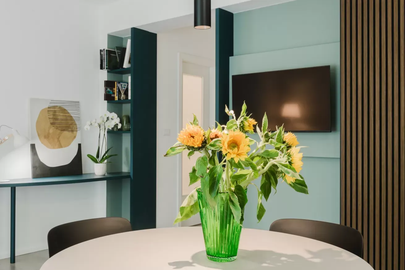 Vaso verde con girasoli su un tavolo rotondo in una sala da pranzo moderna