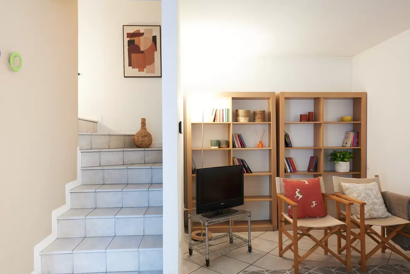 Salotto con scale interne, librerie, TV e due poltrone