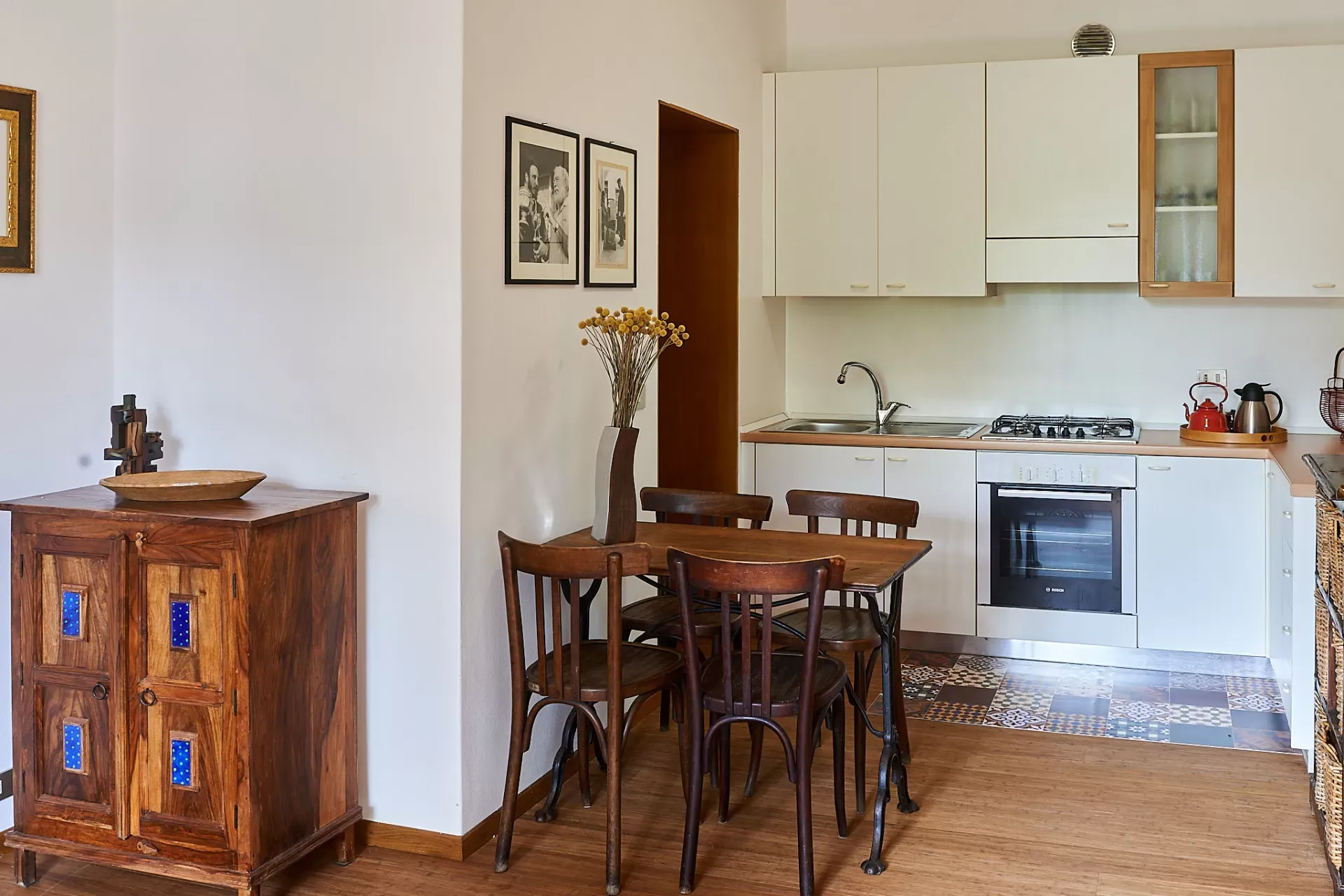 Cucina con tavolo da pranzo in legno, sedie e mobili bianchi, in stile semplice e accogliente