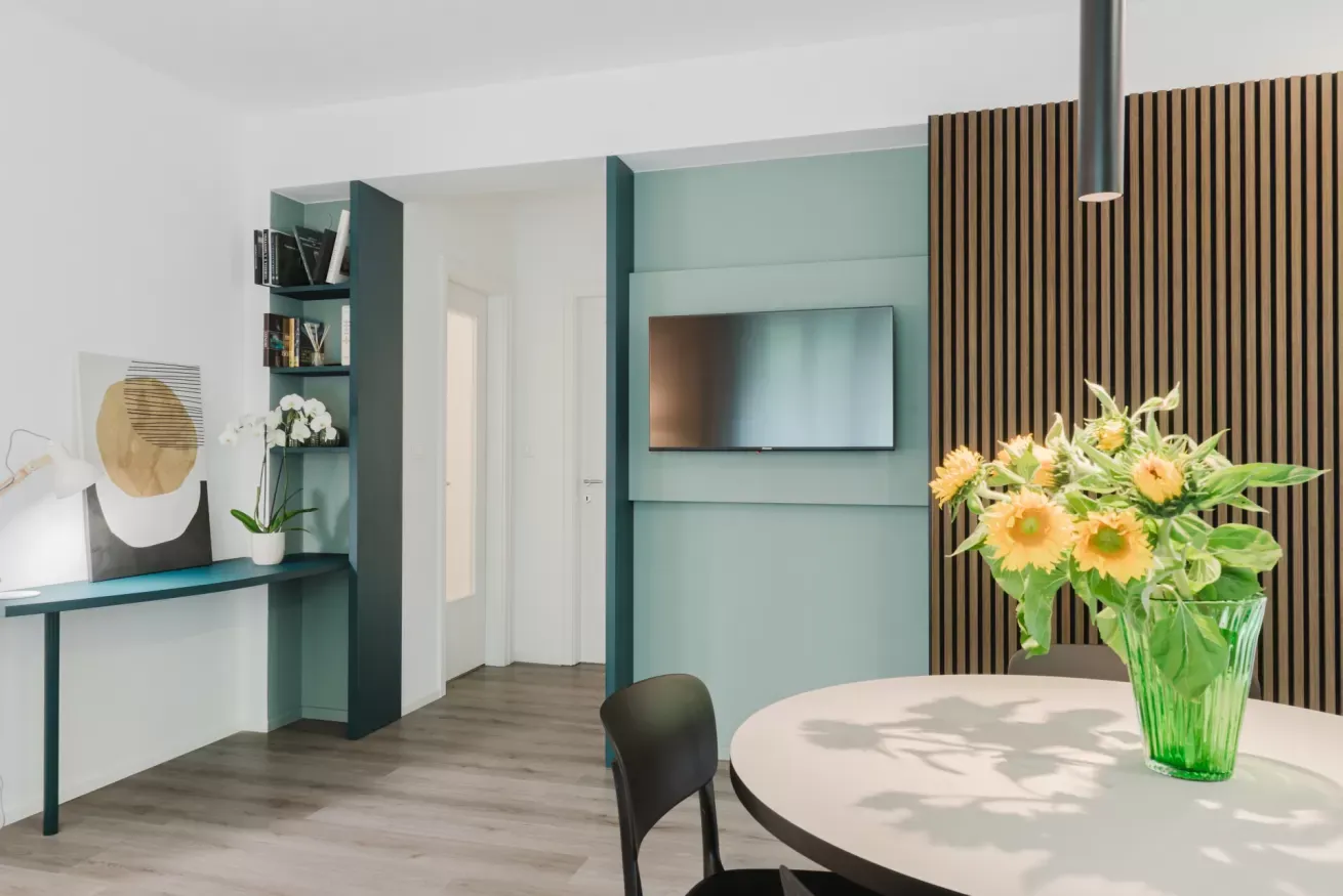 Interno moderno con tavolo, sedia, TV a parete e vaso di fiori gialli su un tavolo rotondo