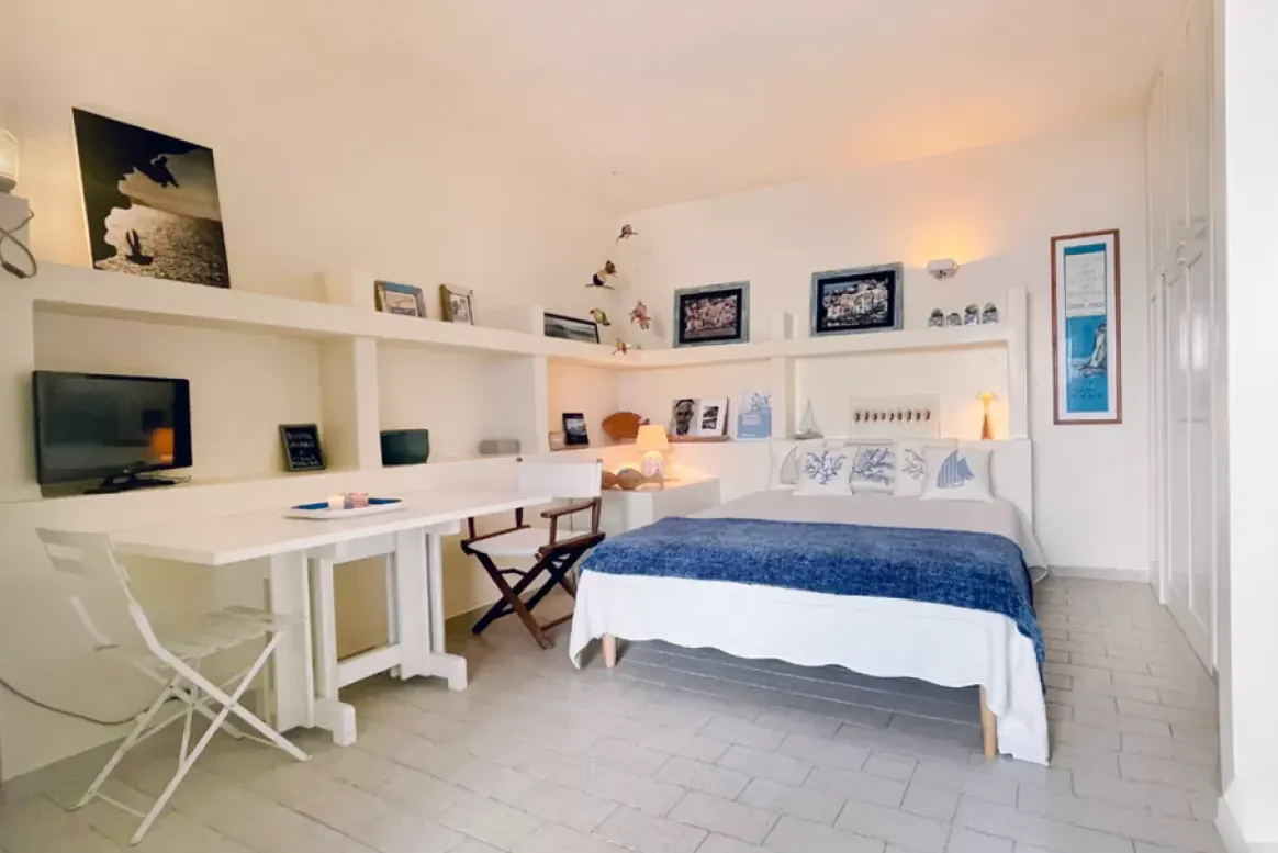 Camera da letto luminosa con letto matrimoniale, scrivania e scaffali a parete