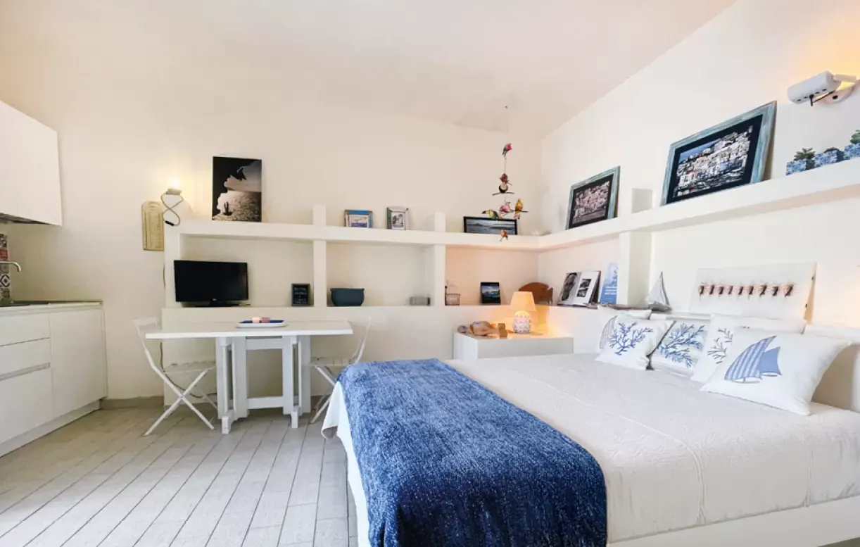 Camera da letto luminosa con letto bianco, scrivania e mensole integrate
