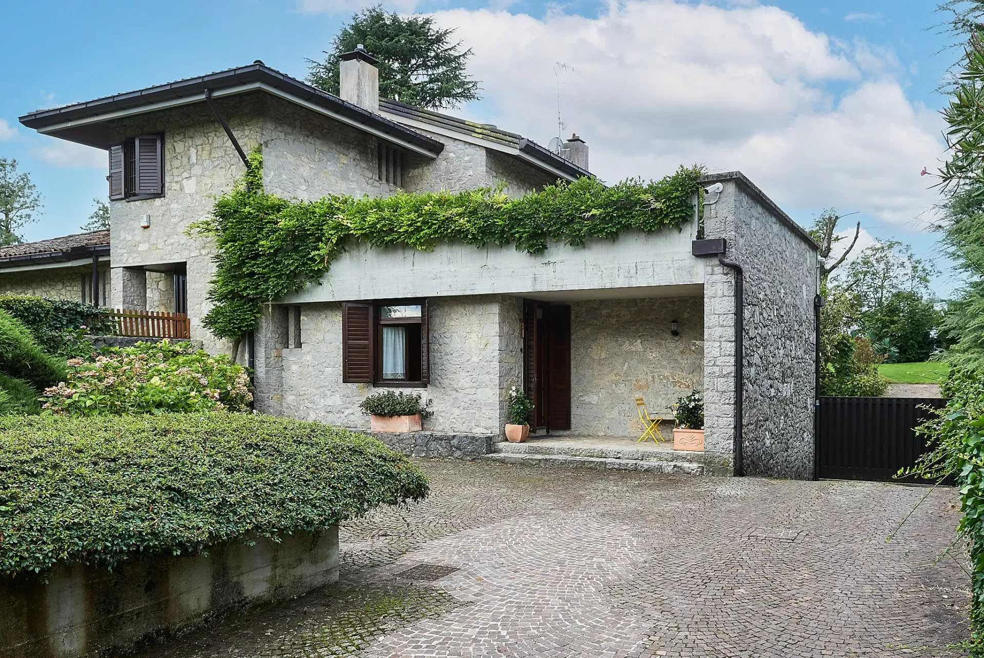 Casa in pietra con cortile pavimentato e giardino curato