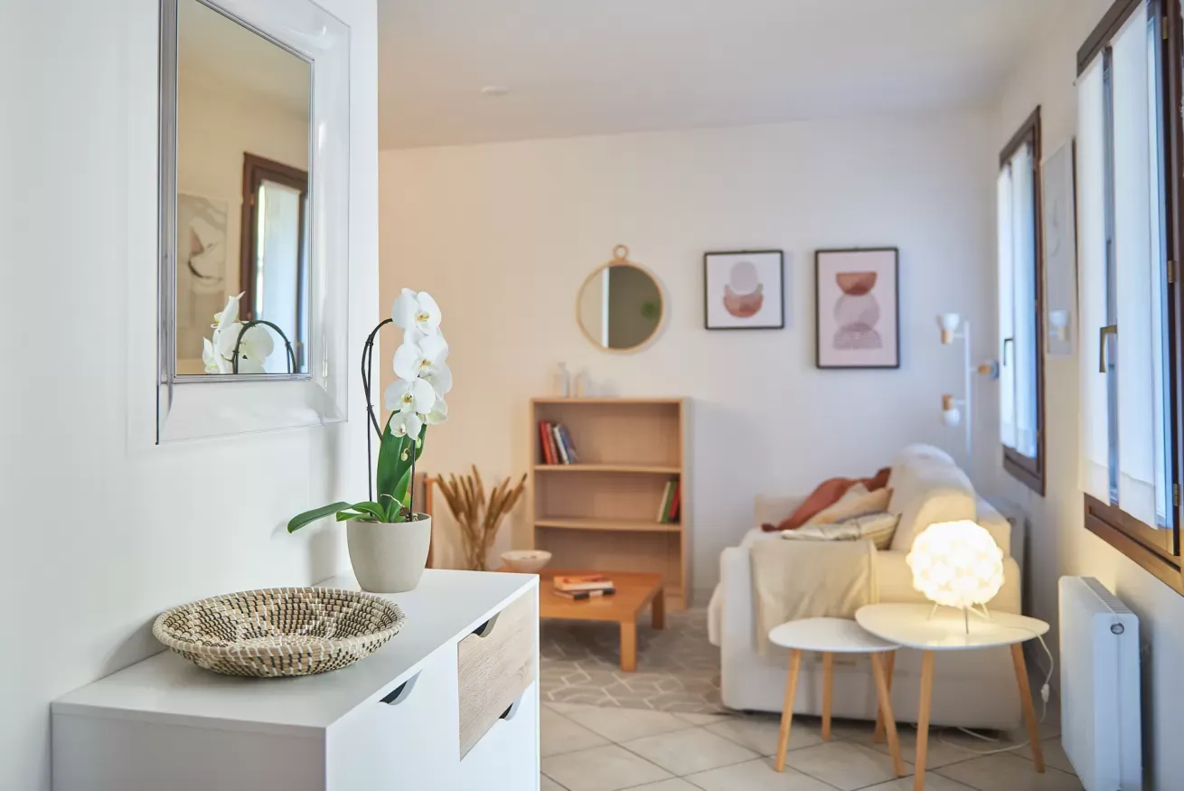 Salotto luminoso con divano, tavolino, libreria e decorazioni minimaliste