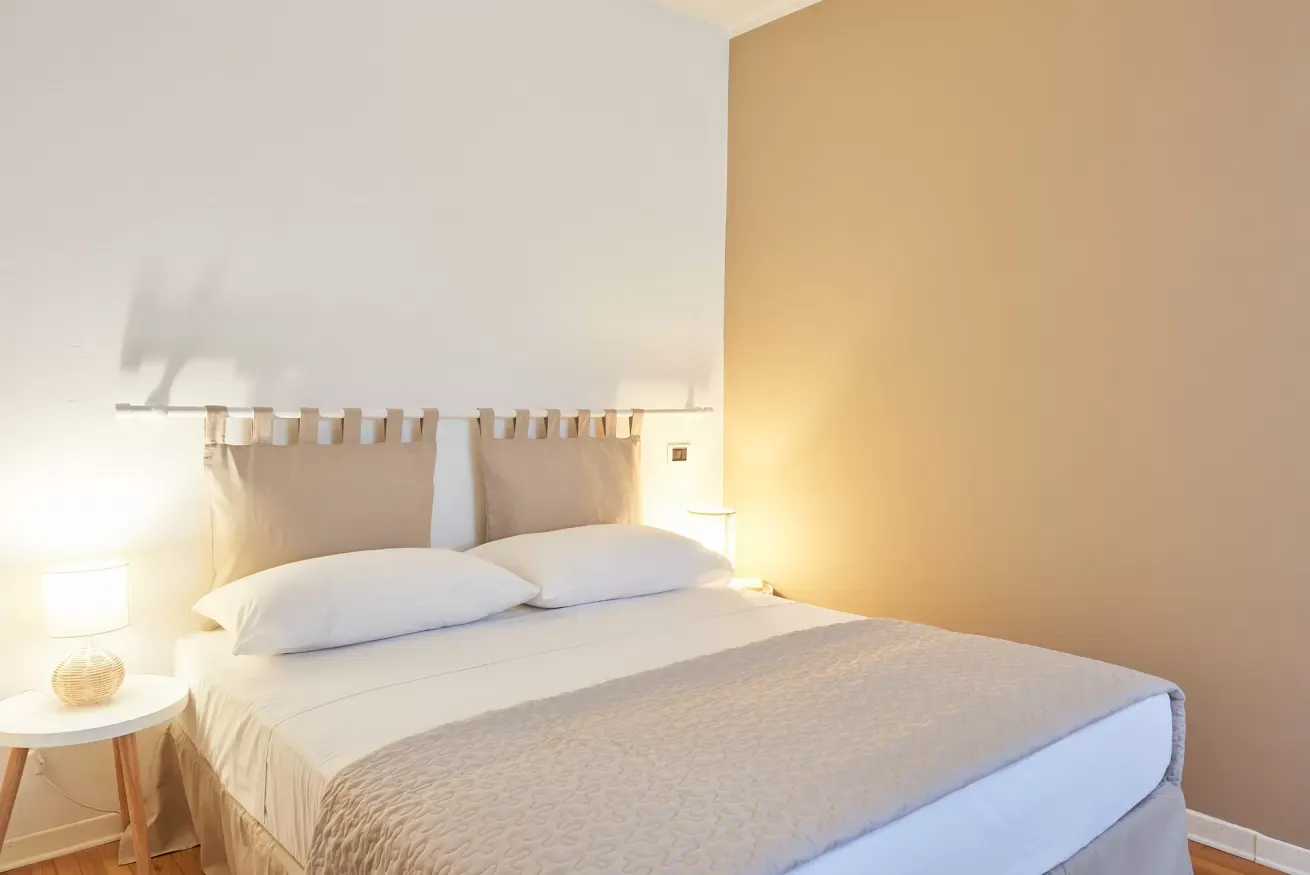 Camera da letto minimalista con letto matrimoniale, comodini e luci soffuse