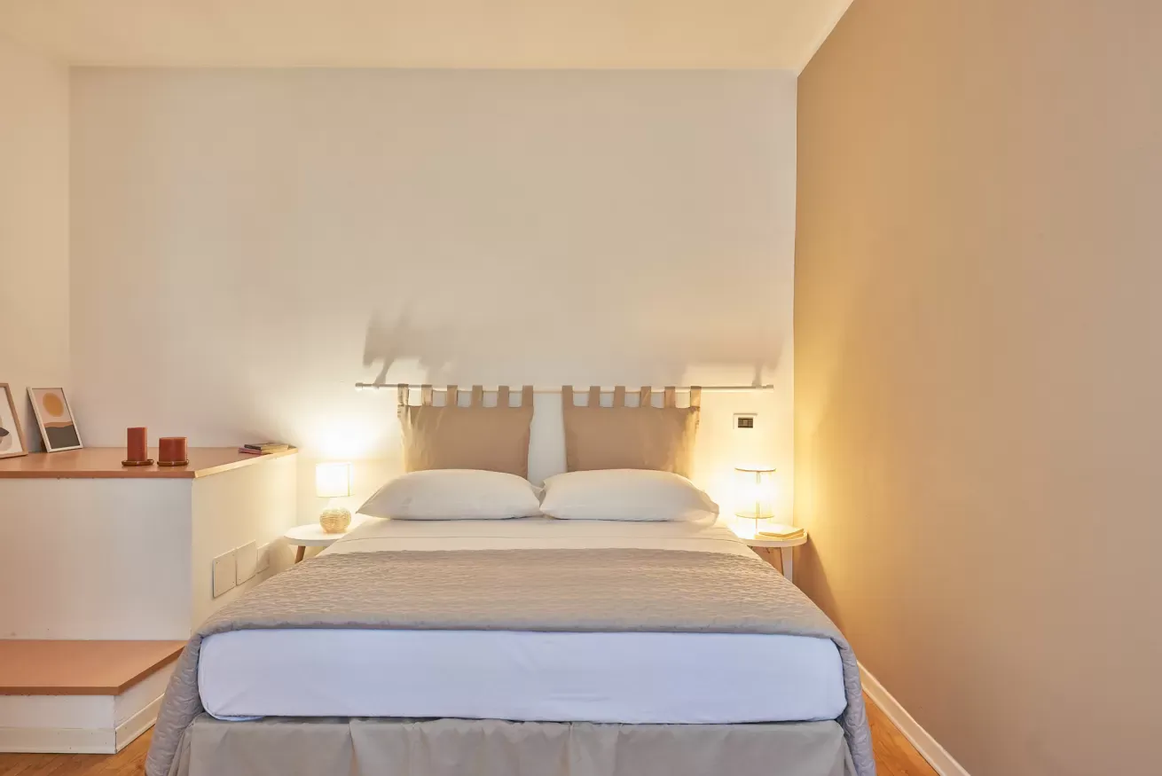 Camera da letto minimalista con letto matrimoniale, comodini e luci soffuse